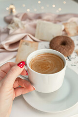 Close-up of a cup of coffee held by a woman's hand.