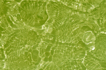 Light green water with ripples on the surface. Defocus blurred transparent colored clear calm water surface texture with splashes and bubbles. Water waves with shining pattern texture background.
