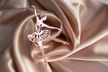 Paper pink ballerina performing a pirouette on a background of pink draped fabric.