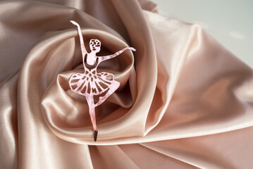 Paper pink ballerina performing a pirouette on a background of pink draped fabric. © Irina Satserdova