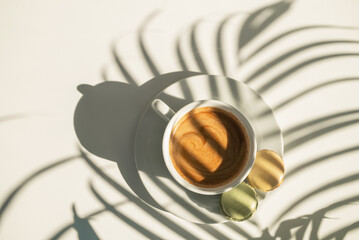 Coffee and cakes on the table with plant shadows