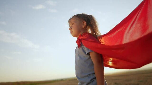 kid superhero. girl daughter happy family a dream concept. baby girl superhero close-up in red cape at sunset. portrait child lifestyle superhero close-up from the back. strength fantasy concept