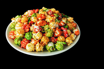A rainbow of sweet popcorn in a plate on a black background