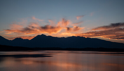Obraz premium Grand Teton Range Stands In Silhouette Under Bright Orange Sky From Jackson Lake