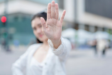 A stern young woman say no, gesturing to stop with her open palm. Rejecting an offer or feeling...