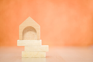Stacking wooden sticks with growing on by steps and home is destinations put on the desk on orange background in the office, Saving money or loan for buy insurance of real estate protection concept.
