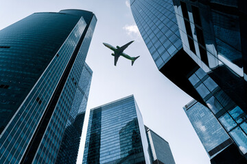 Airplane flying on business skyscrapers of financial center. Travel, economy, cargo, transportation concept