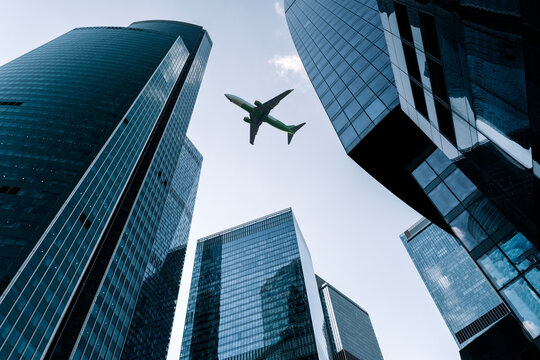Airplane flying on business skyscrapers of financial center. Travel, economy, cargo, transportation concept - Powered by Adobe