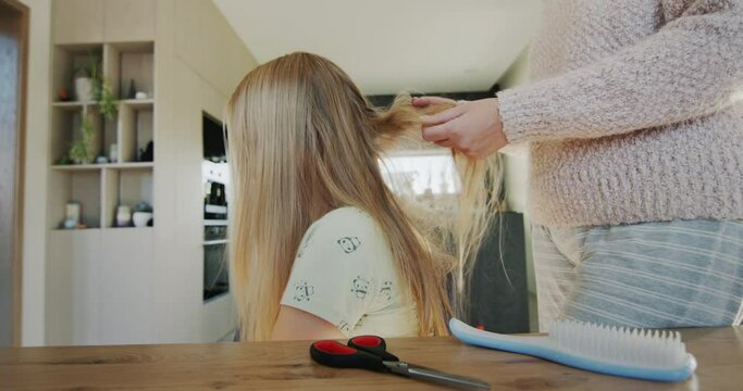 Woman trying to untangle her teenage daughter's long hair