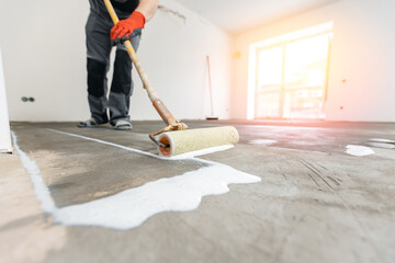 Floor priming process. Worker use primer on concrete floor before laying tiles, strengthening surface