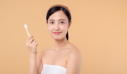 portrait beauty young woman with healthy happy smile holding toothbrush in her hand at morning isolated on beige studio background. hygiene tooth mouth clean care and dental concept.