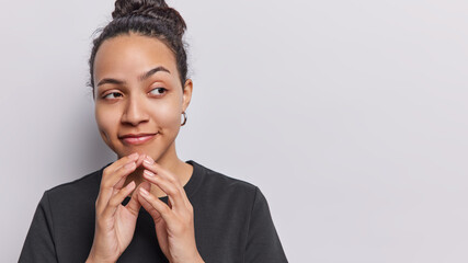 Horizontal shot of beautiful latin woman steeples fingers with thinking face plans and schemes...