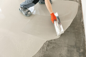 Worker use screed concrete epoxy for level. Leveling with mixture of cement for floors