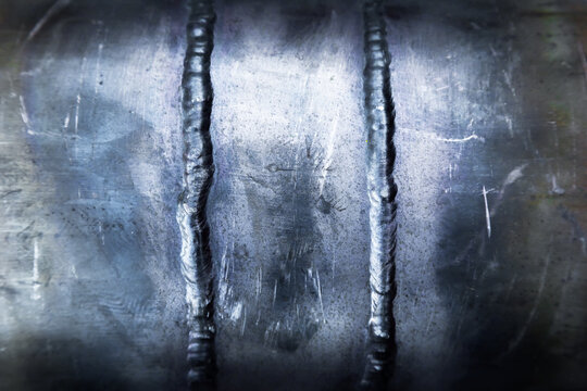 Two vertical welding seams on a steel pipe, close-up.