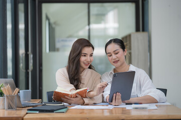 Two Young Asian businesswomen discuss with new startup project Idea presentation and analyze planning and financial statistics and investment market at an office.