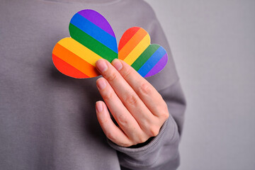 Rainbow heart from paper in woman hands. LGBT flag. LGBTQIA Pride Month in June. Lesbian Gay...