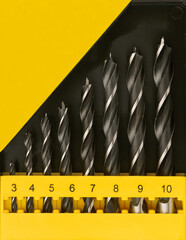 A set of wood drill bits in a plastic box in close-up - 607091810