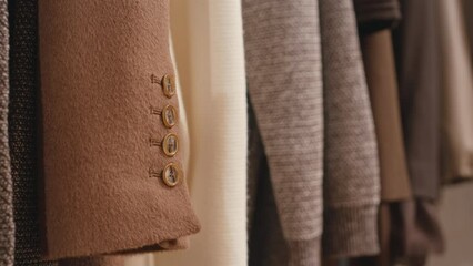No people closeup of elegant wrist buttons on expensive camel wool coat hanging on rack in luxury boutique