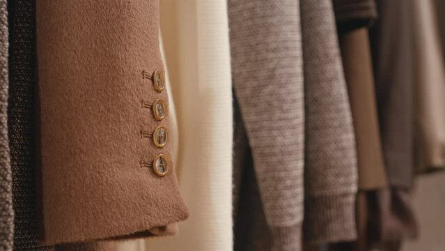 No people closeup of elegant wrist buttons on expensive camel wool coat hanging on rack in luxury boutique