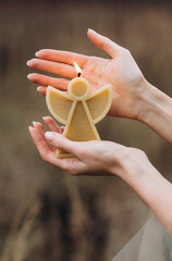  A candle in the form of an angel candle. Brown background. Person holding a candle.Close up. A burning candle.  Romantic  atmosphere. 