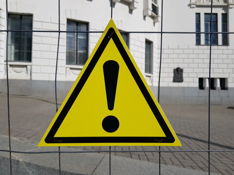 Warning triangle sign on a metal fence.