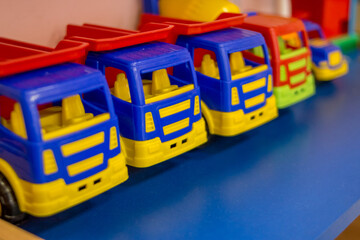 Obraz premium Colorful toy truck. Plastic car.A children's plastic toy trucks with a blue cab and a red body.A sandbox toy. Children's playroom with plastic toy cars.