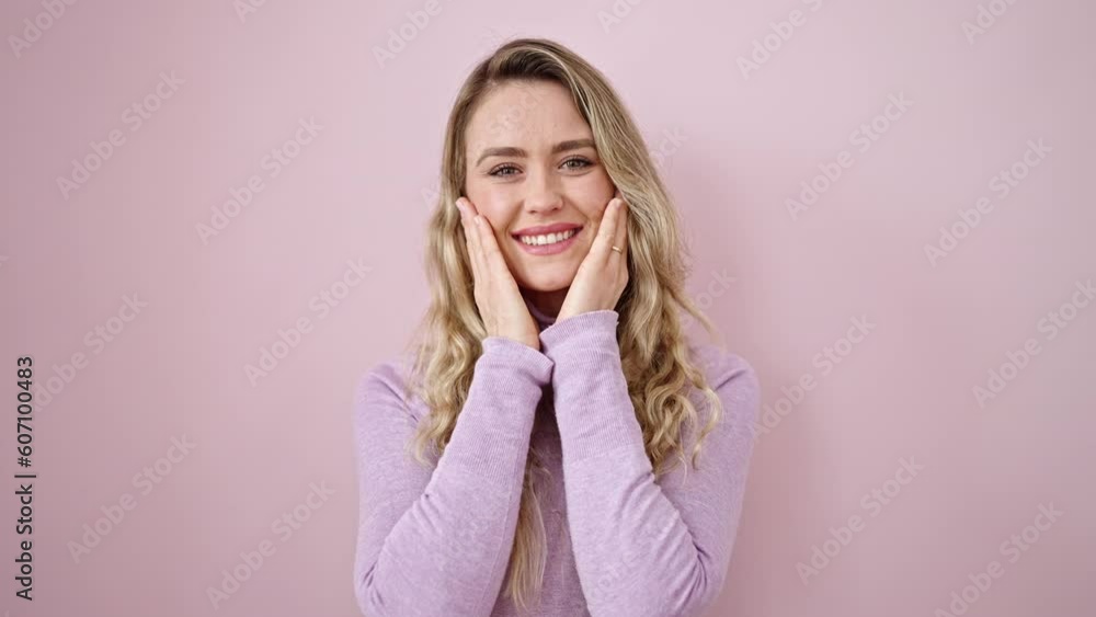 Sticker Young blonde woman smiling confident touching face with hands over isolated pink background