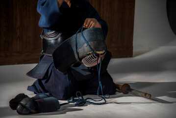 Portrait of man kendo fighter with bokuto Kendo gloves, helmet and bamboo sword on a wooden...