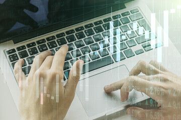 Abstract creative financial graph with hand typing on laptop on background, forex and investment...
