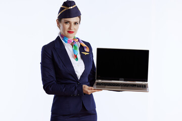 stylish female air hostess on white showing laptop blank screen