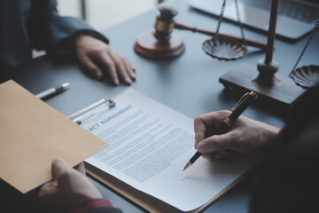 Justice and law concept.Male judge in a courtroom with the gavel, working with, computer and docking keyboard, eyeglasses, on table in morning light