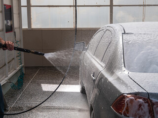 a man washing a car with a special foam of silver color