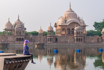 girl on the background of the shrine, sacred place kusum sarovar on govardhan hill, temple in...
