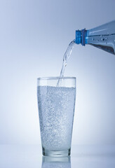 Mineral water is poured into a glass of water