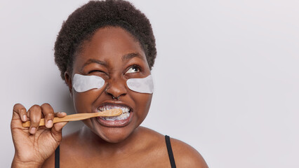 Dark skinned woman brushes her teeth with toothbrush demonstrates importance of daily oral care...