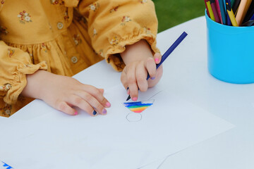 European kid girl painting with colored pencil. Kindergarten children education concept. Close-up...