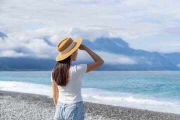 Fototapeta na wymiar Woman with straw hat in the beach with clear blue sky
