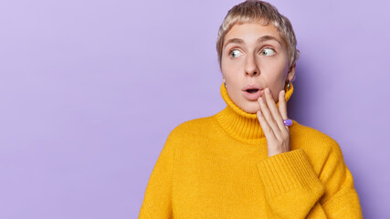 Horizontal shot of impressed short haired woman keeps mouth widely opened reacts to something...