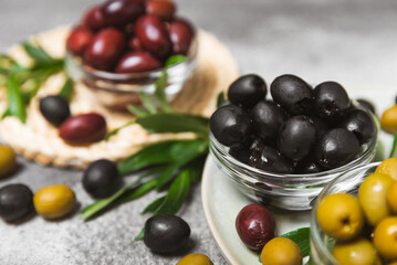 A set of green, red and black olives on a black marble background. Different types of olives in...