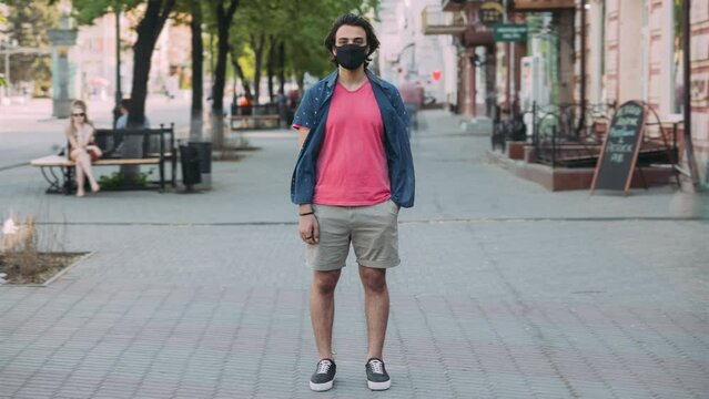 Time lapse portrait of Arab man wearing face mask standing outdoors in crowded street during covid-19 pandemic. City life and epidemic concept.