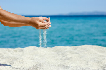 A hands pouring sand near the seashore on weekend nature travel