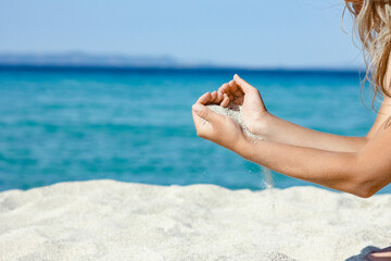 Fototapeta na wymiar A hands pouring sand near the seashore on weekend nature travel