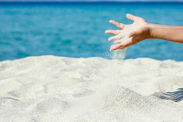 A hands pouring sand near the seashore on weekend nature travel
