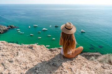 Woman travel sea. Happy woman in a beautiful location poses on a cliff high above the sea, with...
