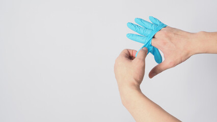 Hand is pulling blue latex gloves on white background.