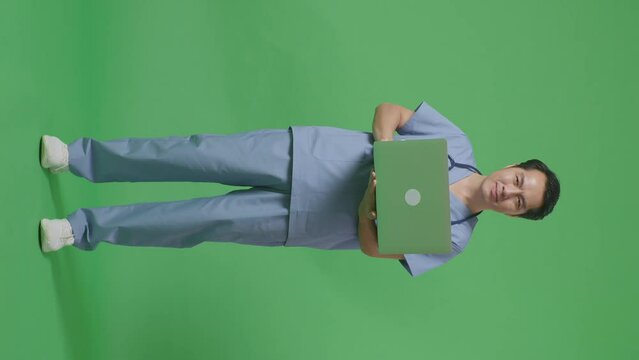 Full Body Of Asian Male Doctor With Stethoscope Holding A Laptop And Smiling On Green Screen Background In The Hospital
