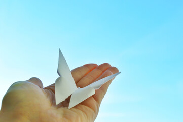 White paper origami butterfly on blue sky background. World Day of Peace. Day Against Humiliation....