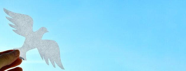 White paper origami bird on blue sky background. World Day of Peace. Day Against Humiliation....