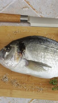 daurade enti&egrave;re, en gros plan, sur une planche &agrave; d&eacute;couper	