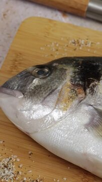 daurade enti&egrave;re, en gros plan, sur une planche &agrave; d&eacute;couper	